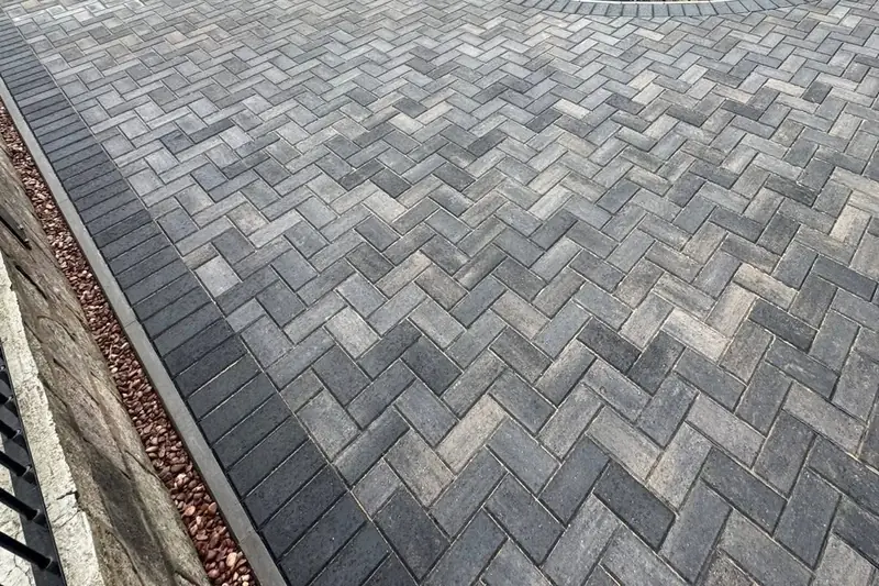 Charcoal and grey block paving laid in a herringbone pattern with a darker charcoal border