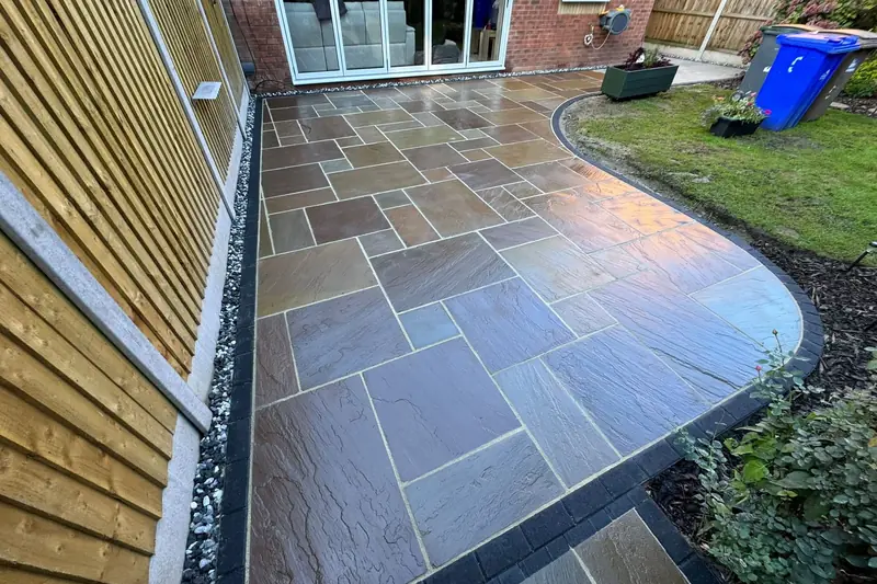 Brown Indian sandstone patio with a sweeping curved charcoal block edge outside bifold doors